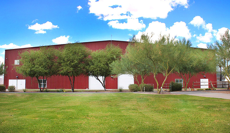 Photo of Rawhide Event Center, a red building with trees lining the front.